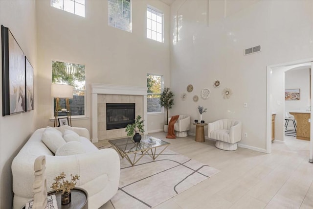 living room with a tiled fireplace and a towering ceiling