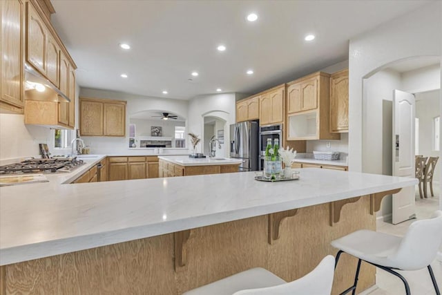 kitchen with kitchen peninsula, a breakfast bar, stainless steel appliances, and ceiling fan