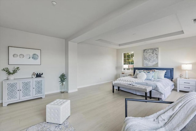 bedroom with light hardwood / wood-style flooring and a tray ceiling