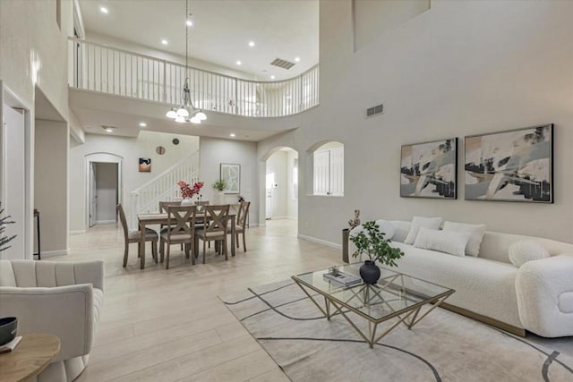 living room with a chandelier, a high ceiling, and light hardwood / wood-style flooring