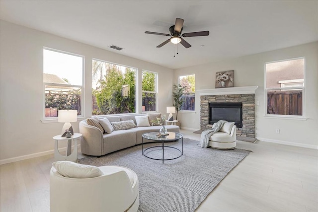 living room featuring ceiling fan, a fireplace, and light hardwood / wood-style flooring