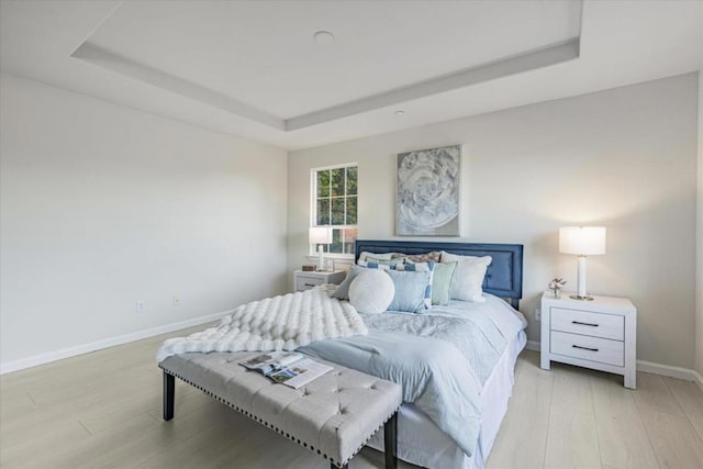 bedroom featuring light wood-type flooring and a tray ceiling