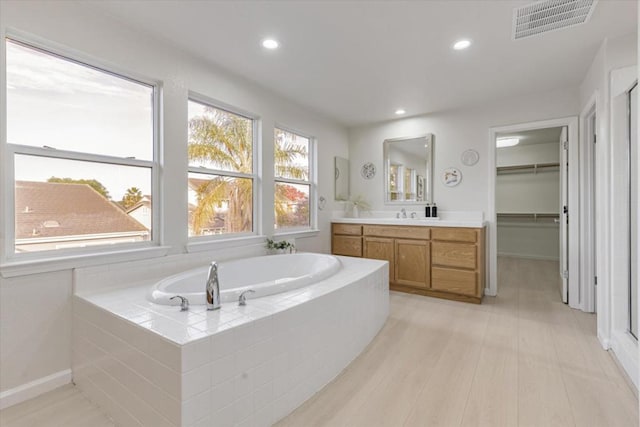 bathroom featuring vanity and tiled bath