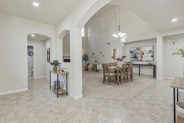 dining space featuring a towering ceiling and an inviting chandelier