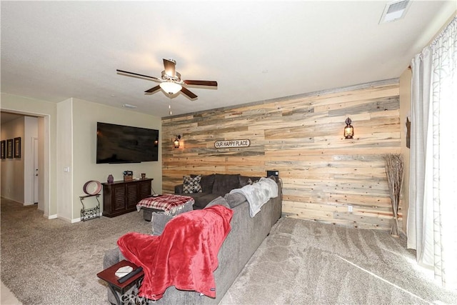 living room with wood walls, ceiling fan, and light carpet