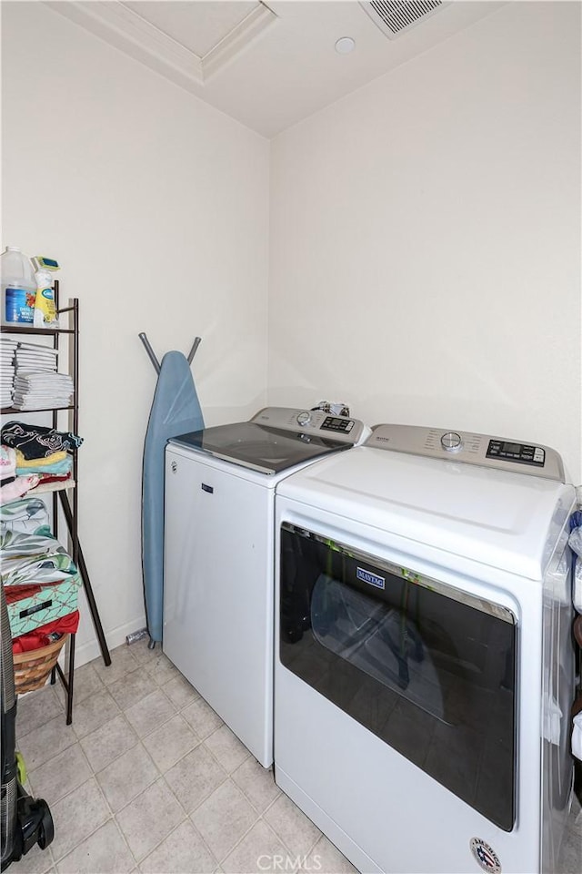 clothes washing area featuring washer and clothes dryer and light tile patterned floors