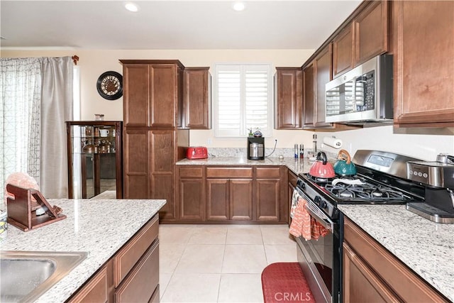 kitchen with light stone countertops, stainless steel appliances, and light tile patterned floors