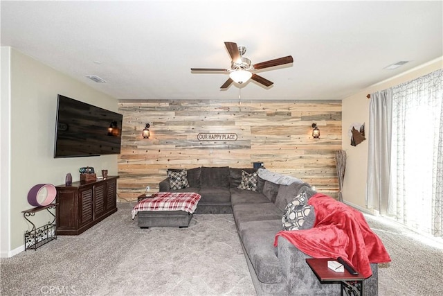 carpeted living room with ceiling fan and wooden walls