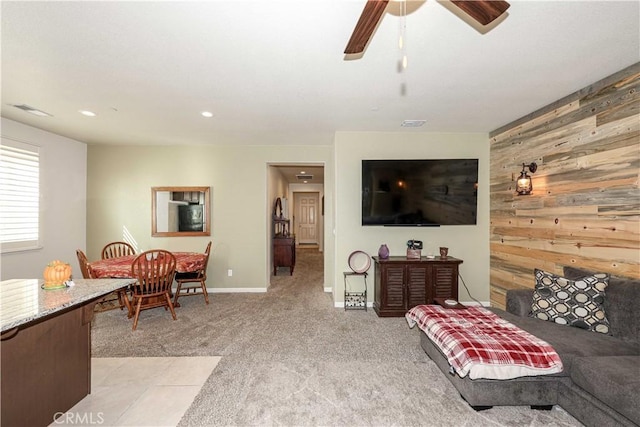 living room with ceiling fan, wood walls, and light carpet