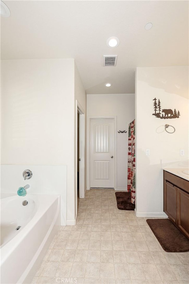 bathroom with a washtub, vanity, and tile patterned flooring