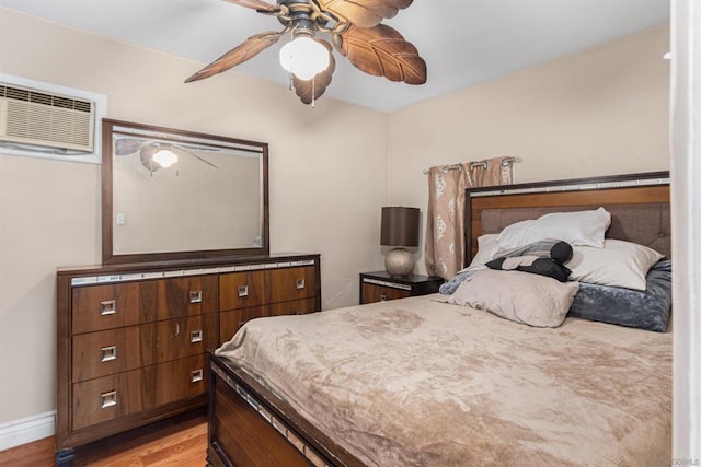 bedroom featuring an AC wall unit, ceiling fan, and light hardwood / wood-style flooring