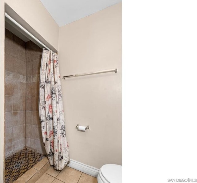 bathroom featuring tile patterned flooring, toilet, and walk in shower