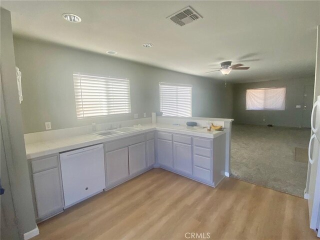 kitchen featuring ceiling fan, sink, kitchen peninsula, white dishwasher, and light wood-type flooring