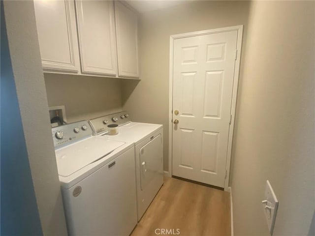 washroom featuring washing machine and clothes dryer, cabinets, and light hardwood / wood-style floors