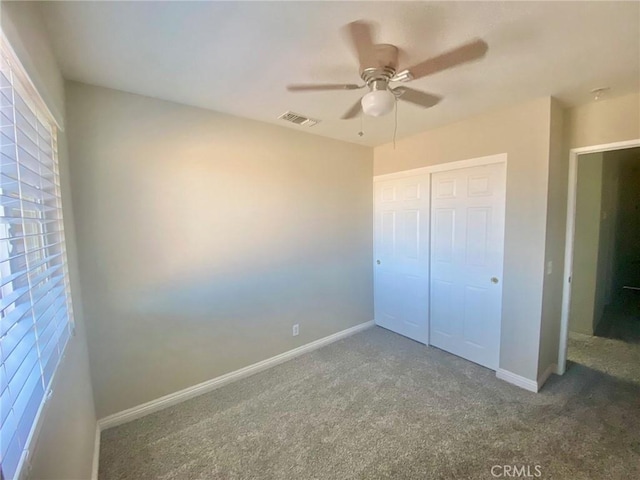 unfurnished bedroom with ceiling fan, a closet, and dark colored carpet