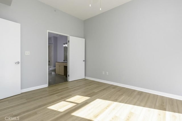 unfurnished bedroom with connected bathroom and light wood-type flooring