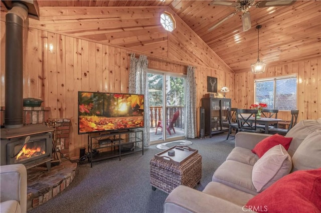 carpeted living room featuring plenty of natural light, ceiling fan, a wood stove, and wood ceiling