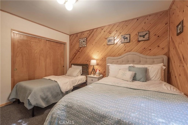 carpeted bedroom with a closet and wooden walls