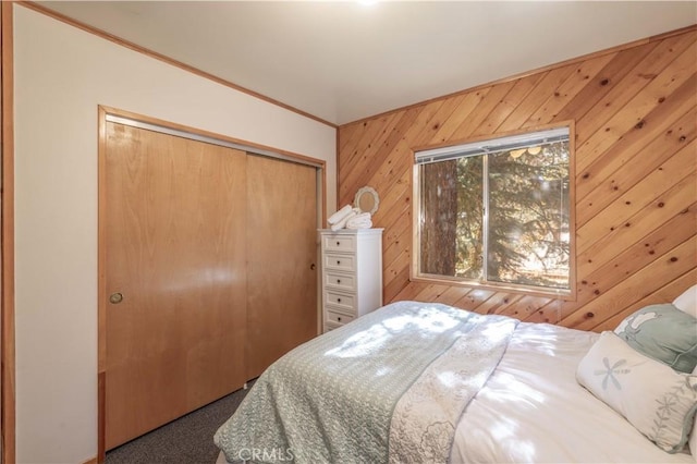 carpeted bedroom with crown molding, a closet, and wooden walls