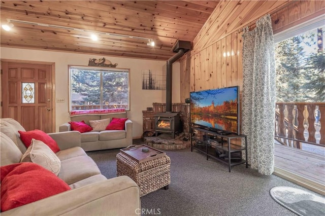 living room with vaulted ceiling, carpet floors, a wood stove, and wooden ceiling