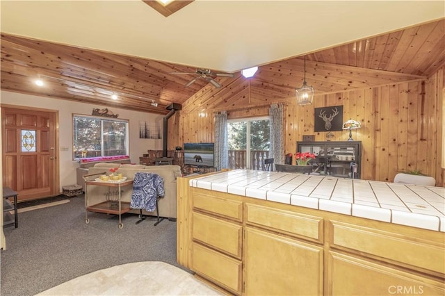 kitchen featuring dark colored carpet, a wood stove, vaulted ceiling, and tile counters