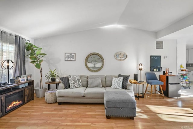 living room with light wood-type flooring and vaulted ceiling