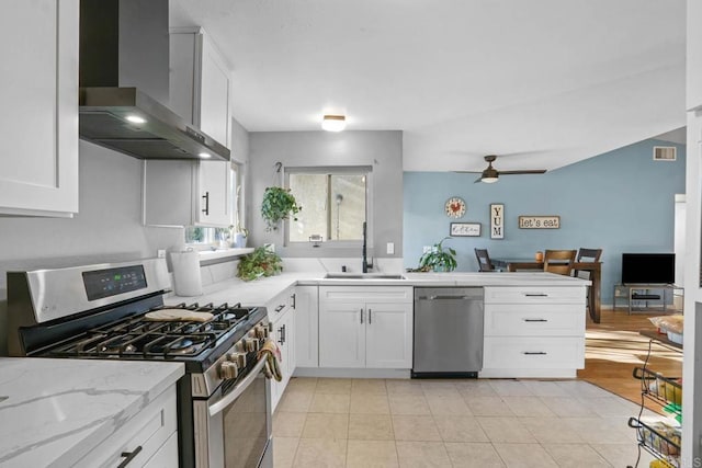 kitchen featuring sink, stainless steel appliances, white cabinetry, and wall chimney range hood