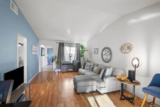 living room with light wood-type flooring and vaulted ceiling