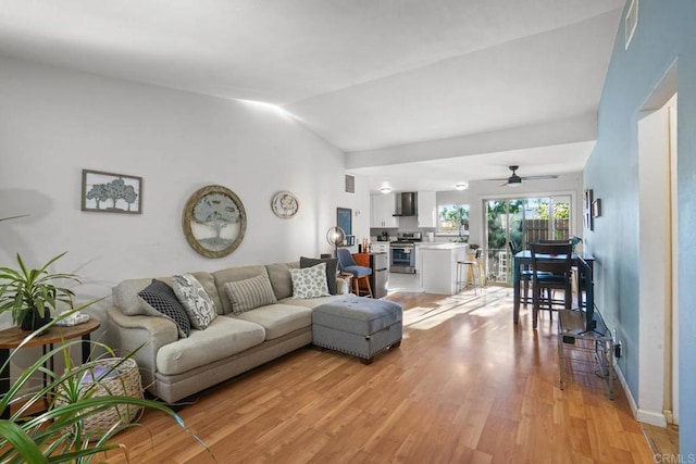 living room with ceiling fan, lofted ceiling, and light wood-type flooring