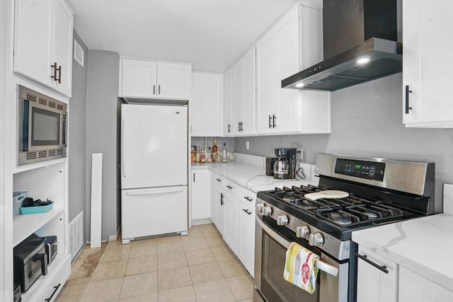 kitchen featuring light stone countertops, wall chimney exhaust hood, stainless steel appliances, light tile patterned floors, and white cabinetry