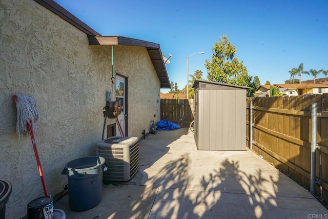 view of patio with central AC unit and a storage shed