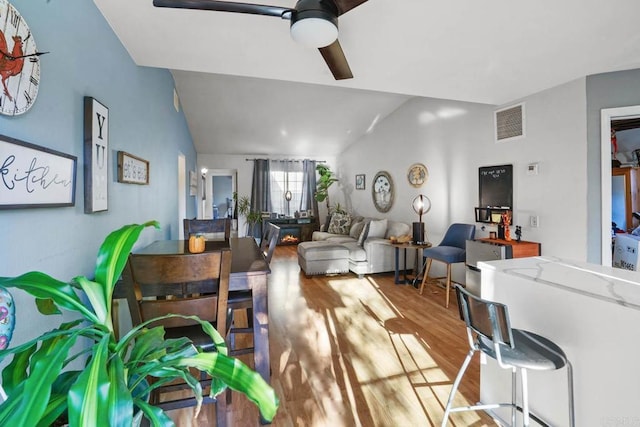 living room with hardwood / wood-style flooring, ceiling fan, and vaulted ceiling