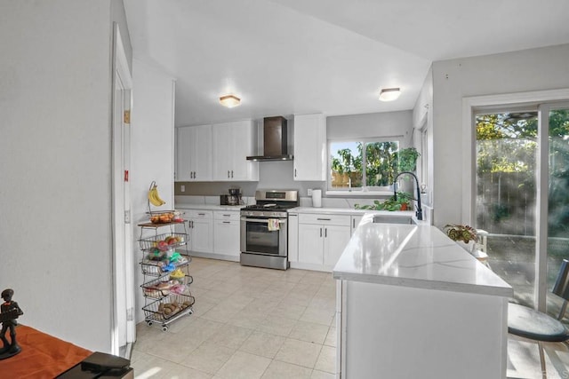 kitchen with white cabinetry, wall chimney range hood, a wealth of natural light, and stainless steel range with gas stovetop