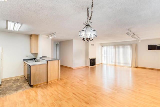 kitchen with light wood-type flooring, track lighting, a textured ceiling, light brown cabinets, and pendant lighting