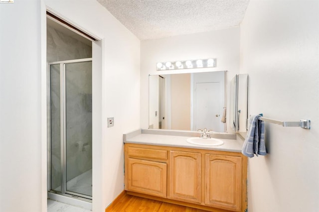 bathroom featuring vanity, wood-type flooring, a textured ceiling, and walk in shower