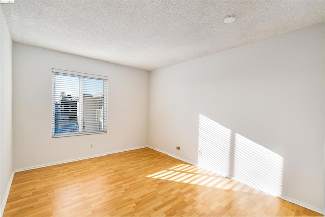 unfurnished room featuring hardwood / wood-style flooring and a textured ceiling