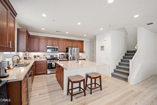 kitchen featuring a kitchen bar, a center island, stainless steel appliances, and light hardwood / wood-style floors