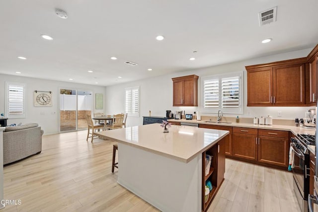 kitchen with plenty of natural light, a kitchen island, stainless steel appliances, and light hardwood / wood-style flooring