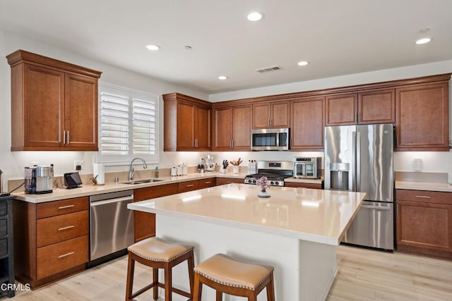 kitchen with a breakfast bar, a center island, stainless steel appliances, and light hardwood / wood-style flooring