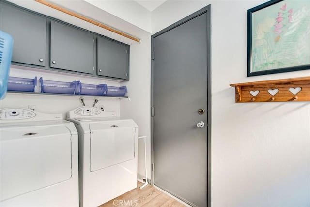 washroom with cabinets, washing machine and dryer, and light hardwood / wood-style floors