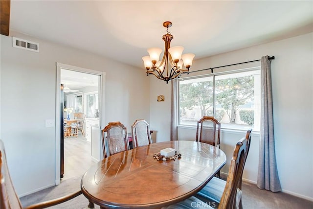 dining area with light colored carpet and a chandelier