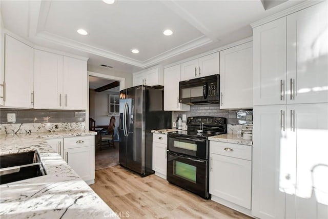 kitchen featuring black appliances, light hardwood / wood-style flooring, a tray ceiling, tasteful backsplash, and white cabinetry