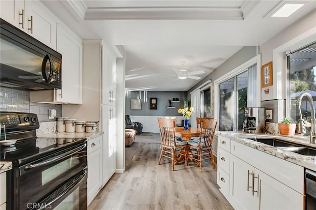 kitchen with light stone countertops, sink, black appliances, light hardwood / wood-style floors, and white cabinetry