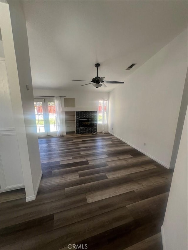 unfurnished living room with ceiling fan, dark hardwood / wood-style floors, plenty of natural light, and a tiled fireplace