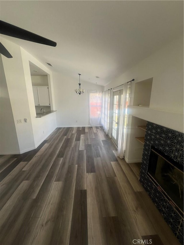 living room with dark hardwood / wood-style flooring, a tile fireplace, and a chandelier