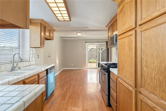 kitchen with tile countertops, a healthy amount of sunlight, sink, and stainless steel appliances