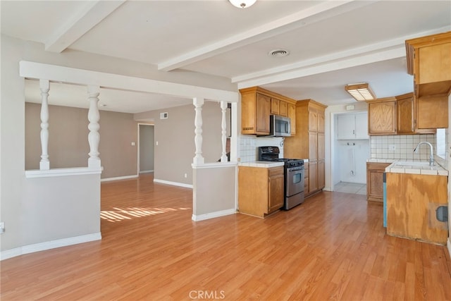 kitchen with backsplash, sink, light hardwood / wood-style flooring, and appliances with stainless steel finishes