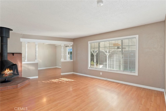 unfurnished living room with a textured ceiling, light wood-type flooring, and a wood stove