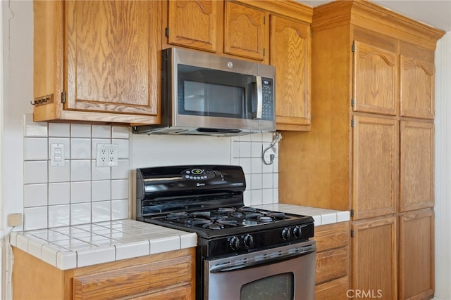 kitchen with decorative backsplash, appliances with stainless steel finishes, and tile counters