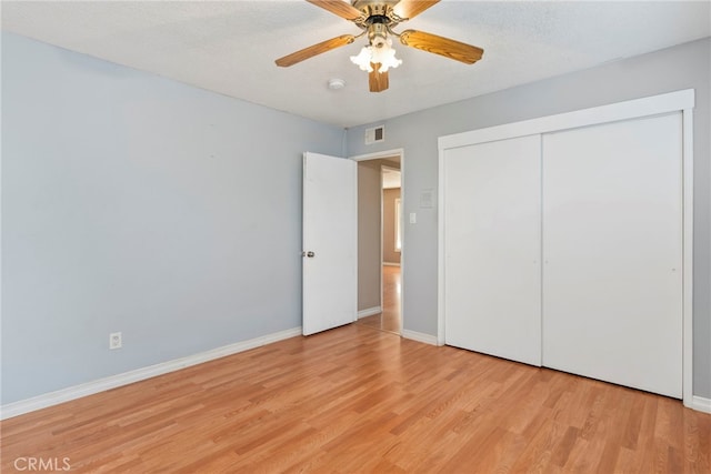 unfurnished bedroom with a textured ceiling, ceiling fan, light hardwood / wood-style flooring, and a closet